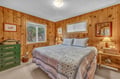 Drift off in your cozy pine-paneled bedroom where warm wood walls embrace you and soft quilted bedding invites deep, restful sleep.