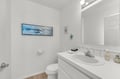 A bright, coastal-themed bathroom awaits you with fresh white surfaces, a soothing ocean-inspired artwork, and thoughtful amenities to help you feel refreshed and at home during your stay.
