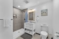 Refresh in your bright, coastal-inspired bathroom with a spacious walk-in shower, elegant vanity, and soothing beachside artwork.
