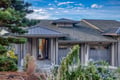 Modern home exterior featuring sleek architectural lines and beautiful landscaping under a dramatic sky.