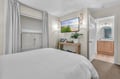 Your peaceful bedroom retreat features crisp linens, entertainment, and serene garden views through soft curtains.