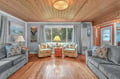 Unwind in your charming living room with stunning wood-beam ceilings, cozy seating, and peaceful garden views through large windows.