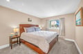 Drift off in your cozy bedroom with plush bedding, warm lighting, and peaceful neighborhood views through the window.