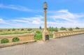 Historic stone bridge landmark with ornate lamp post overlooking coastal meadows under bright blue skies.