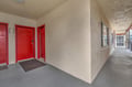 Property exterior showing main building with numbered red entrance doors and covered walkway access.