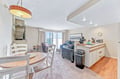 Your coastal retreat features an open living and dining area with a bright kitchenette and stunning ocean views through expansive windows, bringing the calming blues indoors.