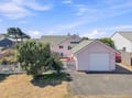 A charming coastal cottage with a private driveway and fenced yard, nestled in a quiet residential neighborhood near the beach.