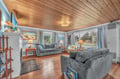 Relax in your spacious living room with vaulted wood ceilings, cozy seating, and peaceful garden views through large windows.