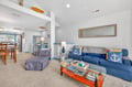 Relax in your nautical-themed living room with a plush blue sofa, charming anchor pillows, and an open layout perfect for unwinding.