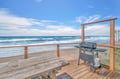 Beachfront deck with BBQ grill offering direct ocean access and stunning sea views for outdoor dining.
