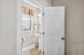 Step into your bright, clean bathroom featuring a pedestal sink and charming window with decorative valance for natural light.
