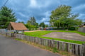 The property is located near a family-friendly neighborhood park with a playground, picnic tables, and open green spaces surrounded by mature trees.