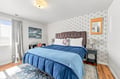 Sink into the plush tufted headboard and wrap yourself in soft blue linens. The elegant accent wallpaper and warm hardwood create a serene retreat for restful nights.