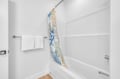 Refresh in your pristine white bathroom with a colorful tropical curtain adding personality to your private retreat.
