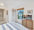 Rest peacefully in your bright, airy bedroom with its crisp white walls and coastal-inspired decor. Natural light floods through the window, while the attached bathroom ensures your convenience and comfort.