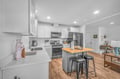 Your modern kitchen features sleek white cabinets, stainless steel appliances, and a convenient breakfast bar where you can enjoy morning coffee.