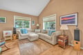 Sink into plush sectional seating surrounded by warm wood floors and peaceful garden views through bright windows.