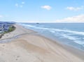 Expansive coastal stretch featuring pristine sandy shores meeting rolling Pacific waves, with residential area nestled along the scenic coastline.