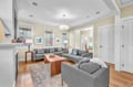 Relax in your elegant living room with plush gray seating, warm wood floors, and peaceful natural light streaming through large windows.