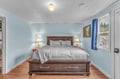 Drift off in your cozy bedroom with soft blue walls, warm wood floors, and peaceful garden views from your window.