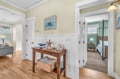 Your coastal-themed hallway welcomes you with warm hardwood floors and charming nautical touches, connecting the inviting living space to your peaceful bedroom retreat.
