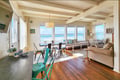 Gather around the dining table or sink into the cozy sofa while you take in stunning ocean views through expansive windows. The warm wood beams and coastal charm make this your perfect beachside retreat.