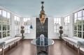 Relax in your sun-filled living space with floor-to-ceiling windows, elegant Moroccan chandelier, and comfortable seating surrounded by garden views.