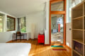 Your modern bedroom blends warm wood floors with forest views, creating a peaceful sanctuary with bright glass doors opening to your private deck.