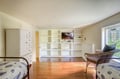 Cozy twin bedroom with built-in storage shelves, flat-screen TV, and garden views creating a bright, welcoming retreat.