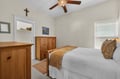 Peaceful bedroom retreat with warm wood furnishings, crisp linens, and gentle ceiling fan for your comfort.