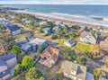 Aerial view of a charming beachfront community with diverse coastal homes nestled among trees, just steps from pristine sandy shores.