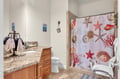 Step into your coastal-themed bathroom with granite countertops, ocean-inspired shower curtain, and thoughtful beach decor that makes every moment feel like vacation.
