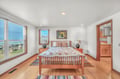 Wake up to stunning ocean views from your comfortable bed in this bright, coastal bedroom with warm wood accents and serene atmosphere.
