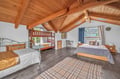 Drift off beneath stunning exposed beams in this spacious bedroom featuring multiple beds perfect for family gatherings.