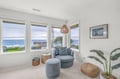 A peaceful corner retreat captures stunning ocean views through three windows. The cozy seating and natural coastal décor create your perfect spot to unwind and watch the waves.