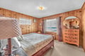 Wake up to stunning ocean views in your cozy wood-paneled bedroom, where the warmth of rustic charm meets the beauty of beachfront living.