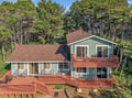 This charming coastal retreat sits nestled among tall pines, offering multiple levels of wrap-around deck space perfect for relaxing outdoors. The natural wooded setting provides peaceful privacy while keeping you close to all the area's attractions.