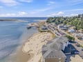 An aerial view captures the property's stunning coastal setting, with sandy beaches, scenic waterways, and lush wooded hillsides creating a peaceful seaside escape.
