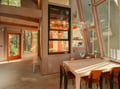 Warm sunlight streams through expansive windows, illuminating your dining space where wood and glass create perfect forest harmony.