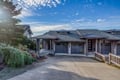 Modern coastal architecture with attached garages nestled among mature landscaping under a brilliant blue sky.