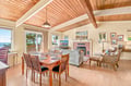 Gather under soaring wood-beamed ceilings in this bright, open space where meals and memories blend seamlessly—your dining table and cozy living area await, just steps from ocean views.