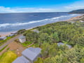 Aerial view showcasing the property with sweeping ocean vistas and rolling waves along the shoreline.