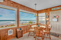 Wake up to stunning ocean waves right outside your window in this cozy dining nook with warm wood paneling and coastal charm.
