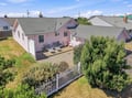 An aerial view captures this charming pink cottage nestled in a quiet residential neighborhood, featuring a private patio and lush greenery surrounding the property.