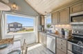 This charming coastal kitchen features vaulted ceilings and a coastal view. Modern appliances and ample counter space make meal prep easy while you enjoy glimpses of the ocean nearby.
