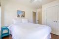 Sink into crisp white linens and let the gentle ceiling fan lull you to rest in your peaceful bedroom retreat, complete with artwork and a charming turquoise nightstand.