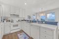 Prepare your favorite meals in this bright kitchen featuring crisp white cabinets, modern appliances, and coastal blue accents. Windows frame stunning ocean views, making every moment here feel like a true escape.