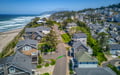 Coastal community nestled between ocean waves and forested hillside, featuring beach access and scenic Pacific Northwest surroundings.
