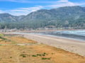 A sweeping coastal community nestled between forested mountains and pristine sandy beaches, offering stunning natural beauty and seaside charm.