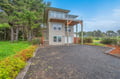 This modern coastal property features contemporary architecture with multiple outdoor decks and sits on spacious grounds surrounded by mature trees and lush Pacific Northwest landscaping.